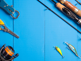 A pair of spinnings, a reel and lures on a blue wooden background.Top of view. Copy space.