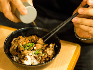 Man hand putting pepper on his bowl of chicken teriyaki