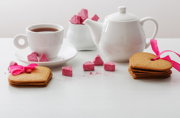Granulated pink sugar  in the shape of heart and cup of tea  on white background