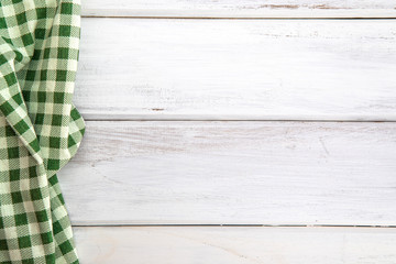 The Crumpled green checkered tablecloth or napkin on empty white wooden table with copy space for food cooking  menu background concept , top view or overhead shot