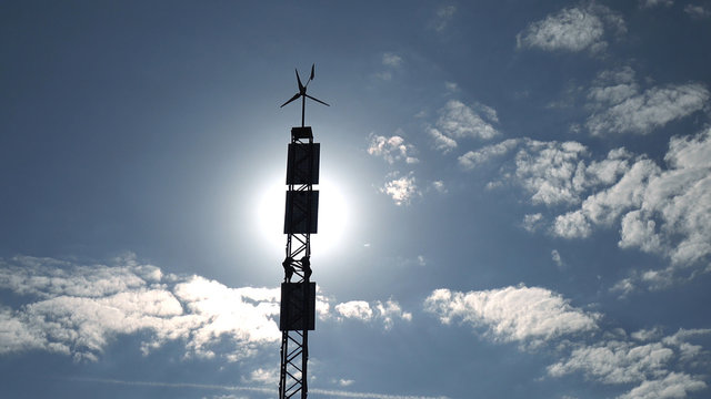 Solar panel and wind turbine on the sky background .