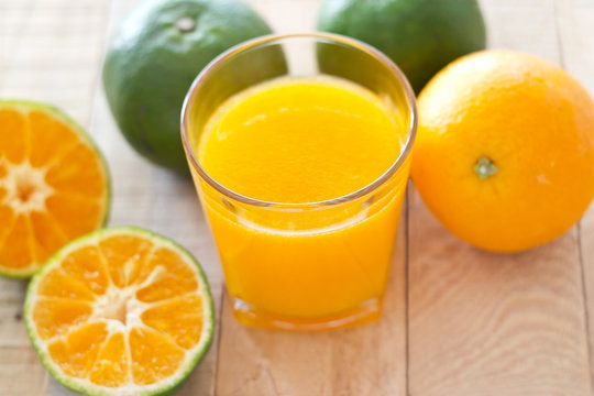 Glass of fresh orange juice on wooden background