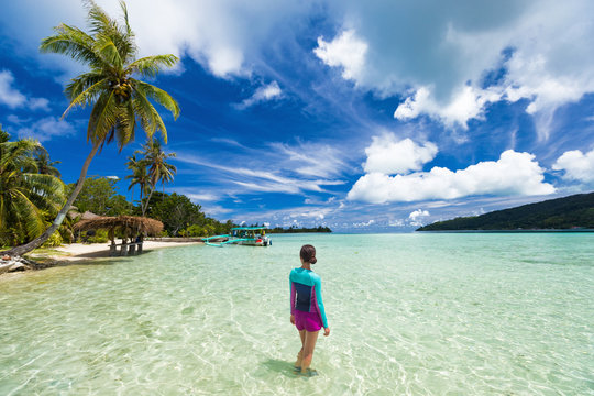 Beach vacation tourist woman swimming in French Polynesia island on cruise excursion at Huahine paradise motu. Tahiti travel holiday. Girl wearing sun protection clothing rashguard for solar skincare.