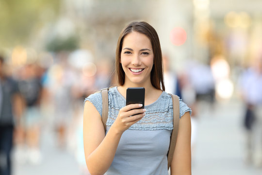 Happy woman holding a phone looking at camera