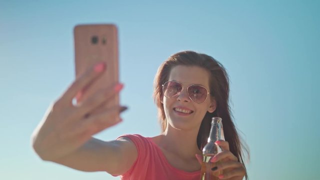 A young lady making a selfie on the beach. Medium shot. Soft Focus.