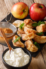 Fried pieces of apples with cinnamon close-up on a table with cream. vertical