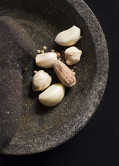 Closeup condiments in stone pot and mortar. Species ingredients concept . Composition of white pepper, nutmeg,candlenut,garlic -  for cooking ingredients. Traditionally used in Indonesia.