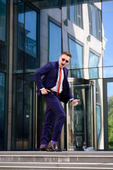 A successful business man dances on the street.