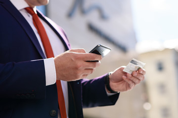 Business man makes a purchase with a credit card via mobile phone.