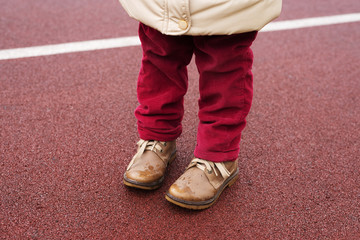 Little girl's legs in red jeans and brown boots