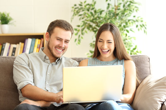 Couple laughing watching on line content in a laptop