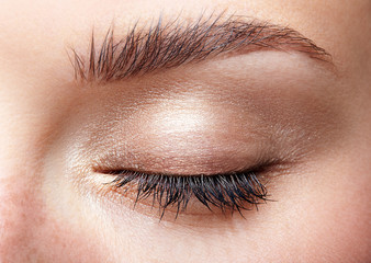 Fototapeta premium Closeup macro shot of closed human female eye with natural day face beauty make up