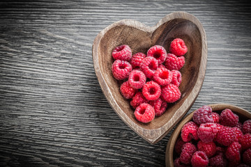 Wooden bowls with raspberries on wood board