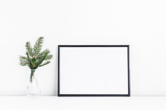 Christmas composition. Black frame and christmas tre branches on white background. Front view, mock up, copy space