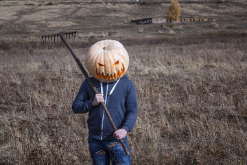 Modern Jack-lantern with a pumpkin on his head standing in the field. Halloween legend.