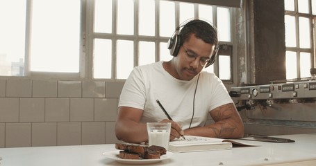 mixed race man drawing in sunny loft listening music in earphonesimages with sunny flairs