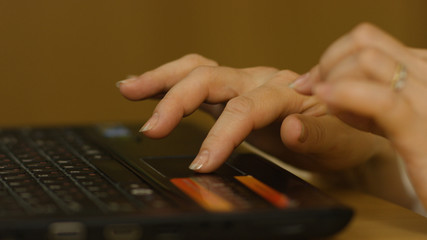 A Woman's hand with the fingers on a laptop mousepad. Woman's hand using laptop mouse
