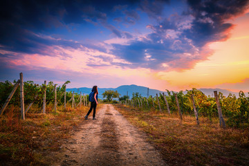 Young girl with a backpack in Bulgarian vineyards on a Sunset ready to travel 