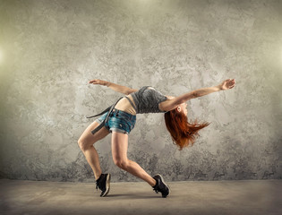 Fototapeta na wymiar Woman dancer in dynamic action on the grunge grey background.