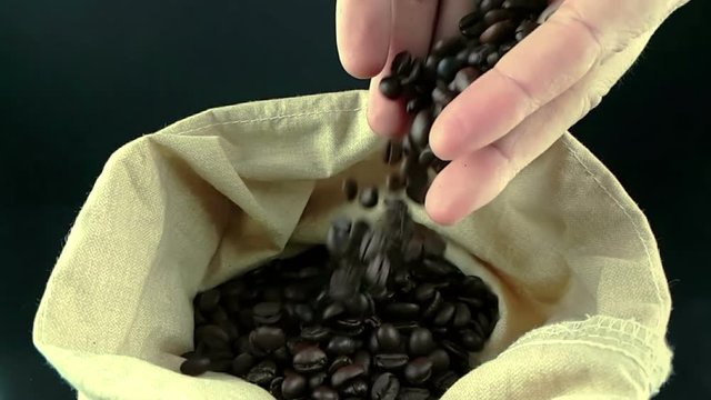 man hands holding coffee beans in canvas sack and some falling down, shot slow motion, agriculture and nutrition concept