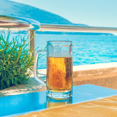 Fototapeta na wymiar Beer in a mug on a table on the background of the sea