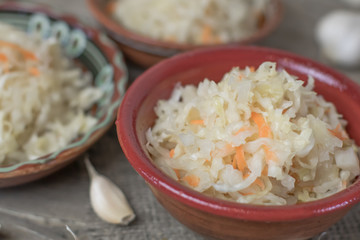Homemade sauerkraut village. Fermented cabbage. Vegan salad rustic style glass jar or ceramic pottery bowl. Fermented food great for good health. Traditional rustic winter food.