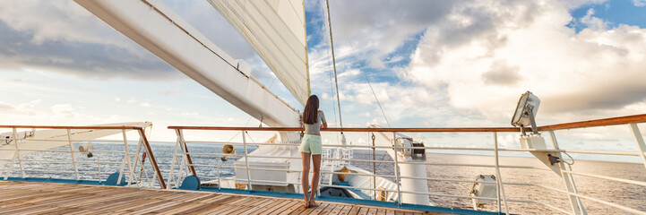 Luxury cruise ship vacation woman on deck banner panorama. Travel in Tahiti on sail boat, exotic destination. Tourism in oceania. Boat sailing away on tropical getaway