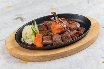 Isolated medium rare wagyu steak topping with mince carrot on hot plate and wooden plate served with potato salad  on washi (Japanese paper).