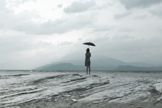 woman with black umbrella looks at infinity in a surreal scene