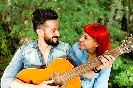 Young couple having fun with guitar in the park.