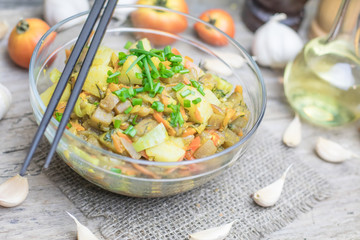 Homemade nutritional vegetable ragout in glass plate bowl on rustic old wooden table. Vegan or vegetarian food diet. Selective focus.