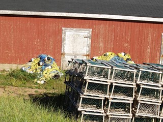 Stack of lobster pots and fishing equpment outside red shed