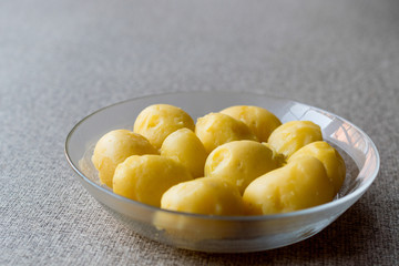 Boiled Potatoes in glass bowl on grey surface.