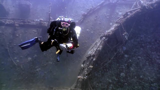 Red Sea, Egypt - 21 June 2015: Scuba divers swimming explore shipwreck Salem Express deep underwater. Secret of sunken ship which crashed on coral reef. Historical place of tragedy.