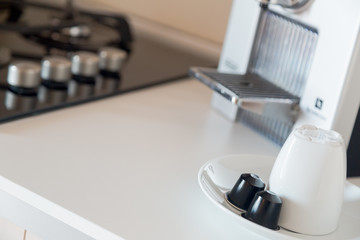 Detail of a kitchen with coffee capsules, white cup and a coffee maker
