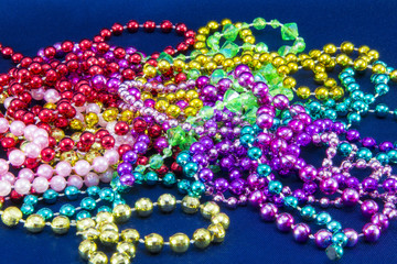 Green, purple, and gold mardi gras beads isolated on blue