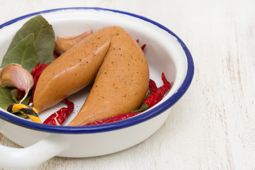 smoke sausage on white dish on wooden background