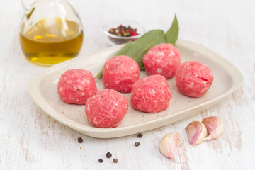 raw meatballs on the dish on wooden background