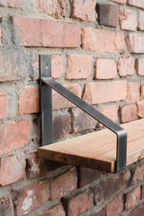 Shelf in wood and metal hanging on a brick wall in loft style