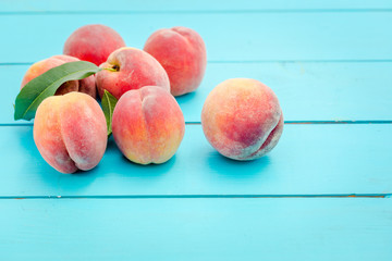 Ripe peaches with leaves on rustic wooden table