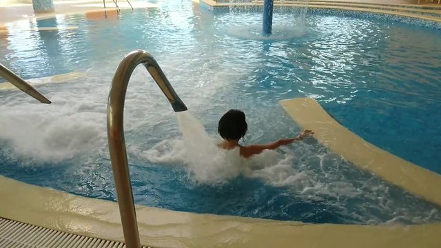 femme dans une piscine sous jet d'eau