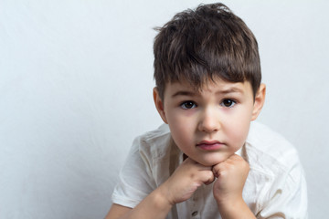 pensive little boy close-up on a white background.