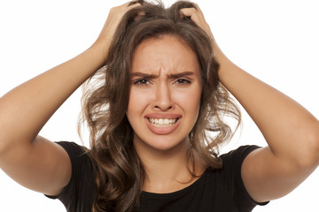 Beautiful young woman has an itch in her hair on white background