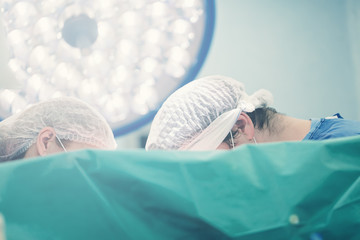 Medical background with team of surgeons doctors illuminated by special surgical lamp lightning...