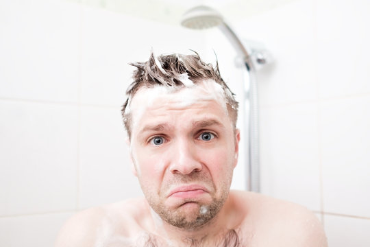 Worried foamed young man after the water in the shower was turned off, looking at the camera.