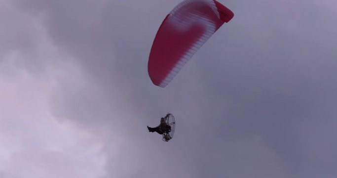 paramotor man flying through cloudy sky 4k