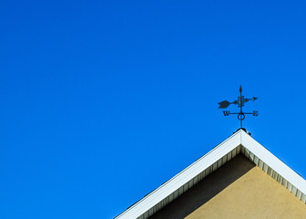 weather vane on house on sky background.