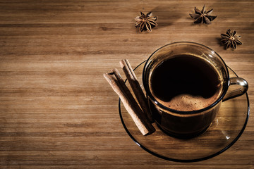 A cup of coffee on a wooden background with cinnamon sticks.  Top view, toning, still life.