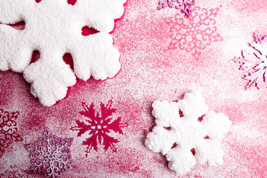 Pink and white snowflakes on a pink background. Christmas background. Top view. Copy space. Decorative snow.