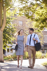 Obraz premium Businessman And Businesswoman Walk to Work Through City Park